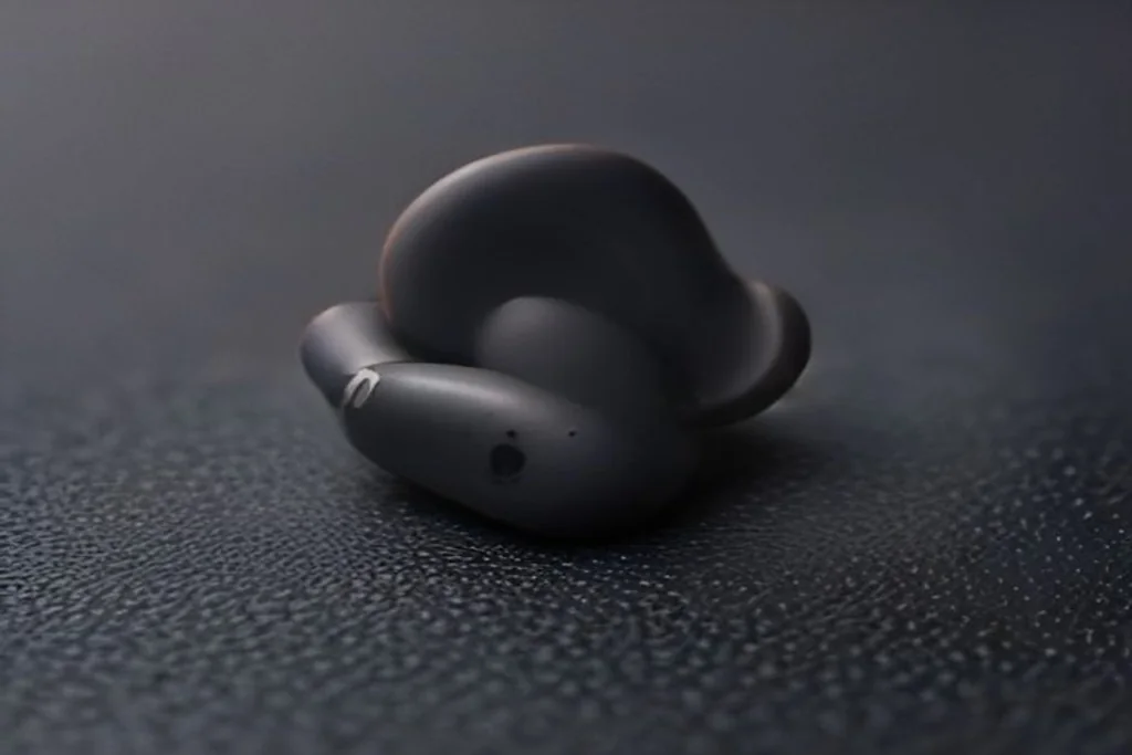 Single earbud macro shot next to silicone ear tips of three sizes on a dark surface